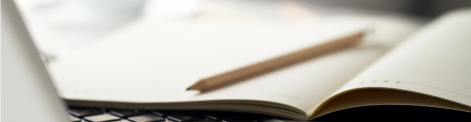 Illustration du copywriting avec un crayon posé sur un cahier, sur le clavier d'un ordinateur portable.