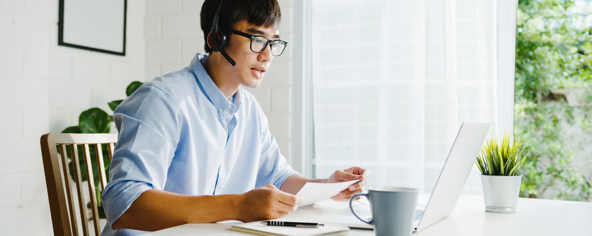 Homme avec casque audio sur les oreilles, travaillant à son domicile où il est locataire, l'ordinateur sur la table du salon